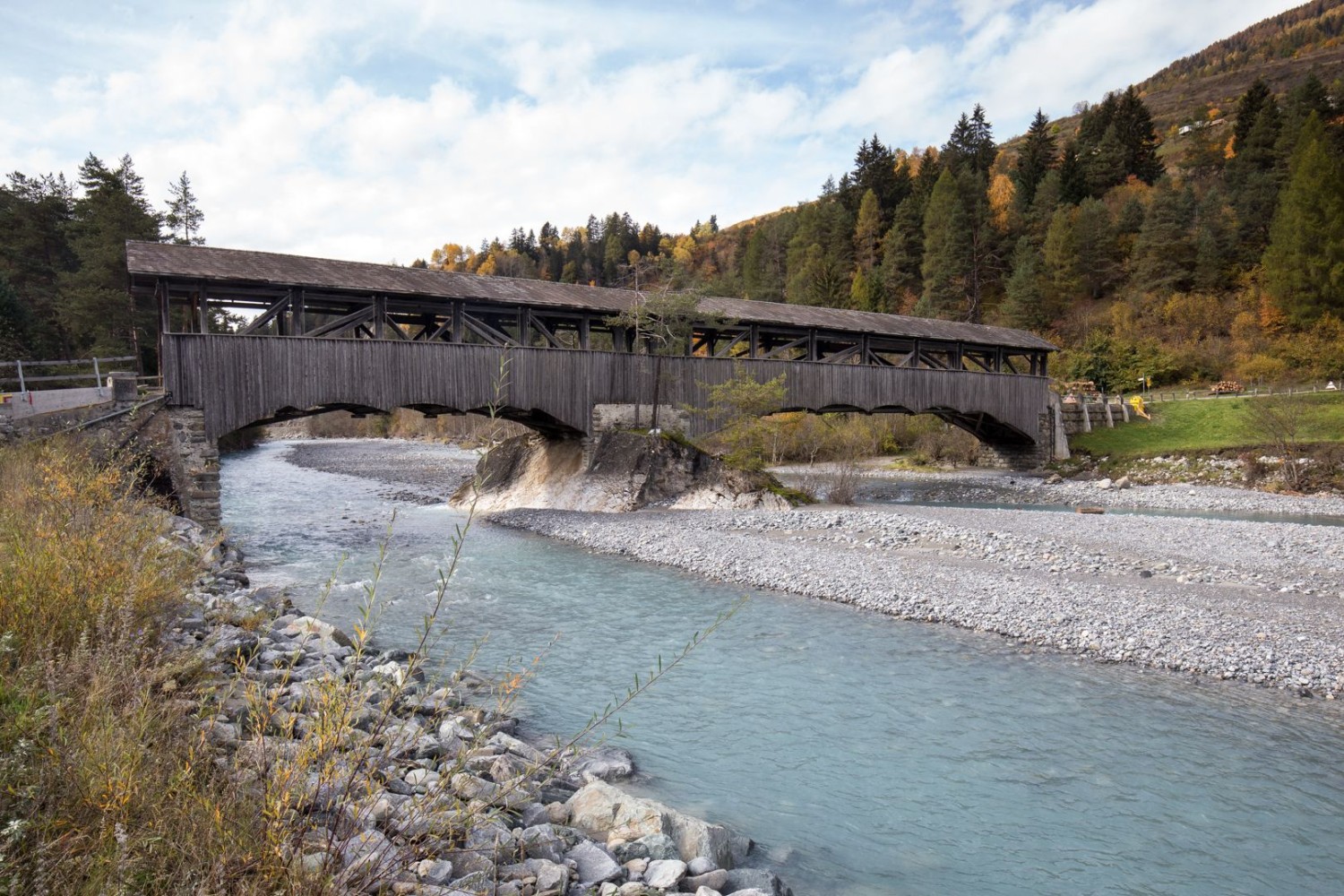 Un vieux pont en bois franchit l’Inn au début du parcours, à Sur En Camping.