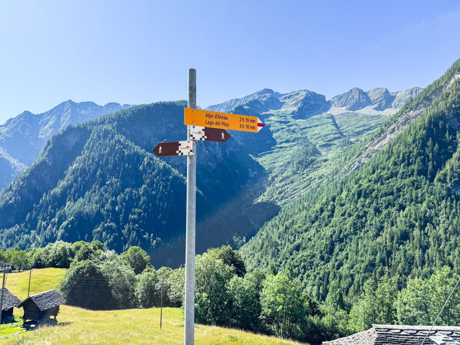 Questo segnavia si trova a Piano di Campo. Sul segnavia non è indicata la meta Linescio, bensì solo Alpe d’Arnau: si segue questa direzione.